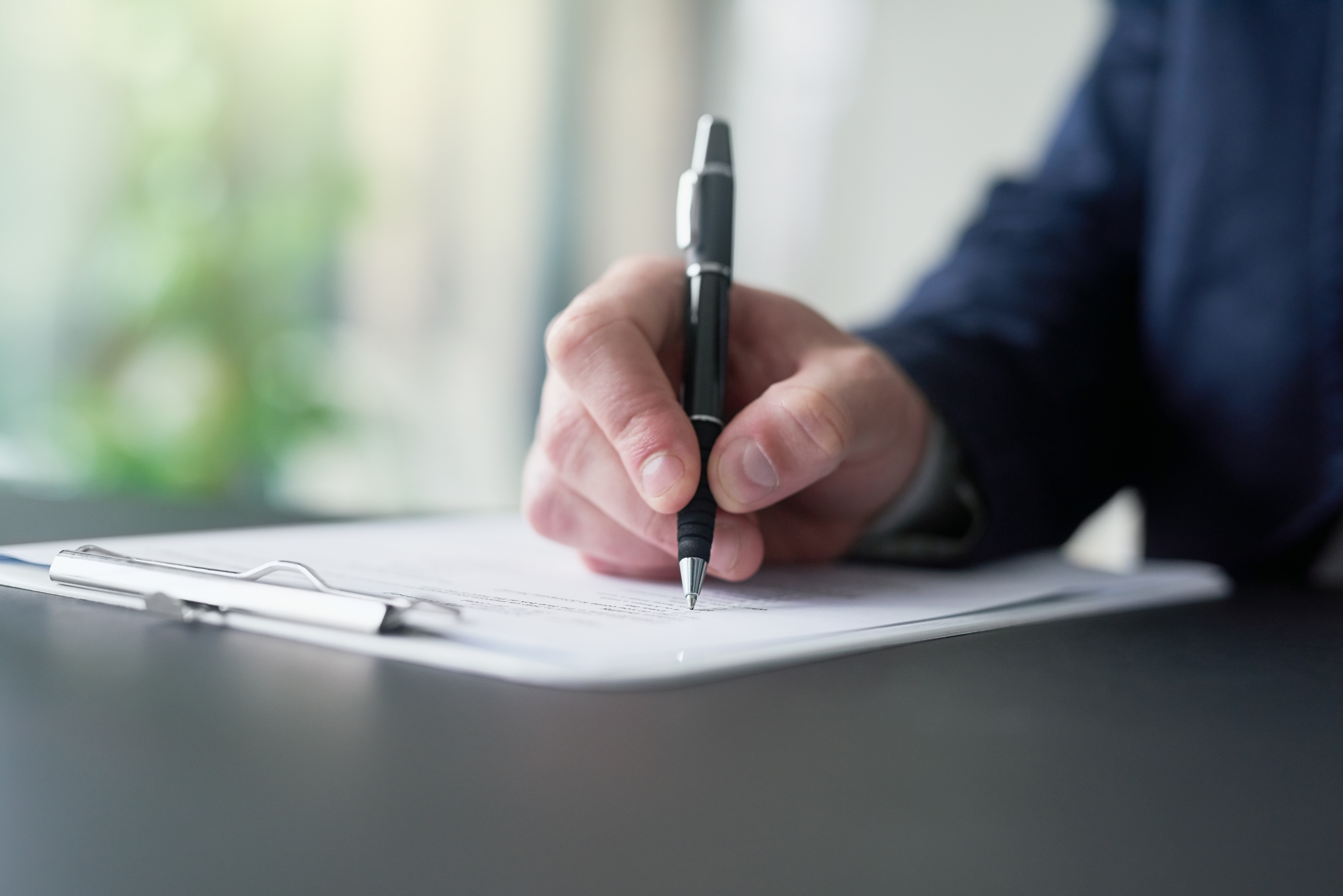 Person writing on a contract with a pen