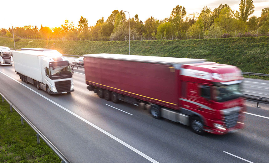 Two large lorries driving side by side on a motorway during daylight