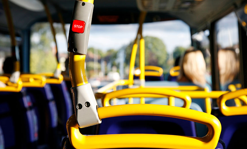 Yellow bus seat handle with a stop button inside a city bus