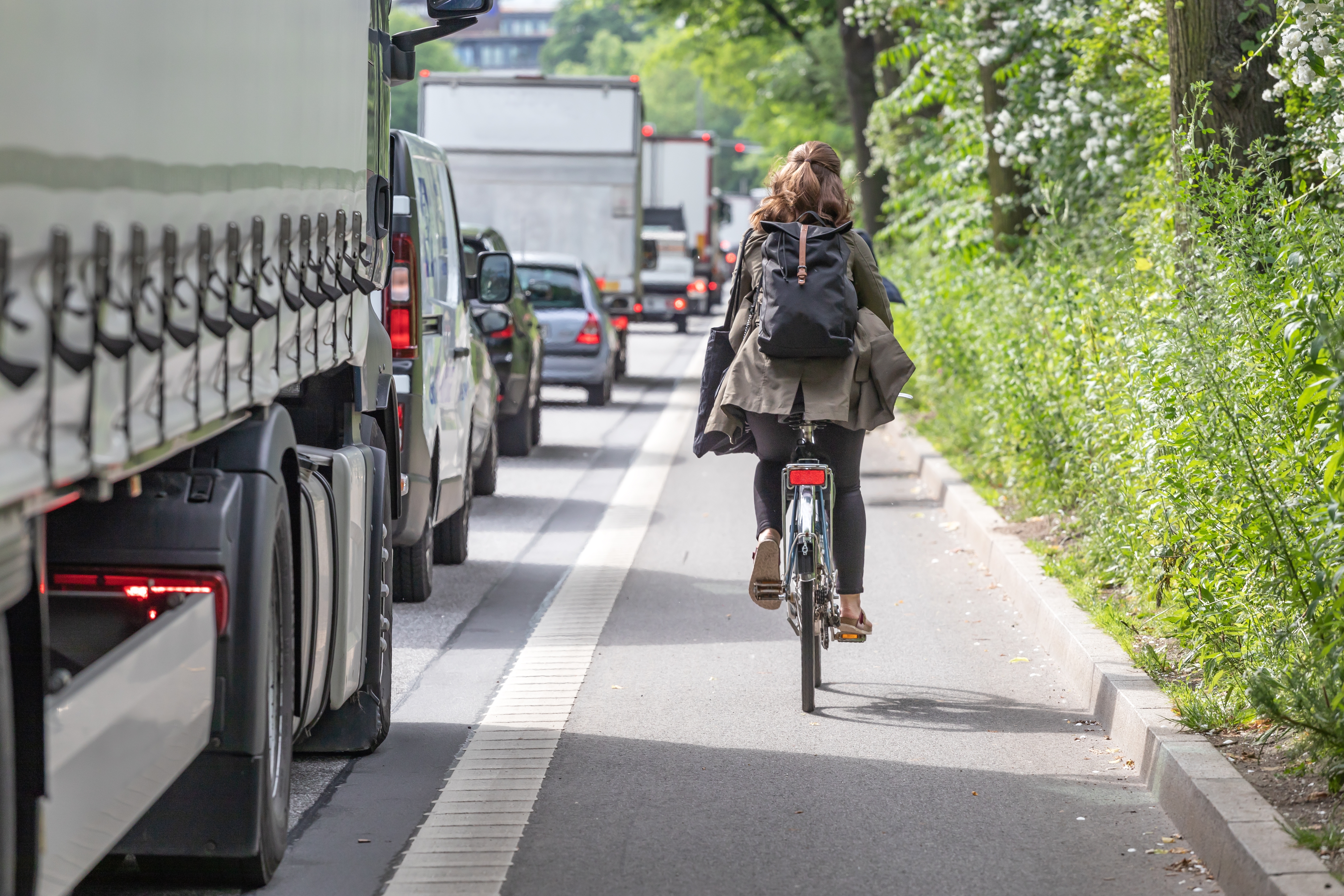 Cyclist riding next to HGV on busy London road, highlighting blind spot risks.