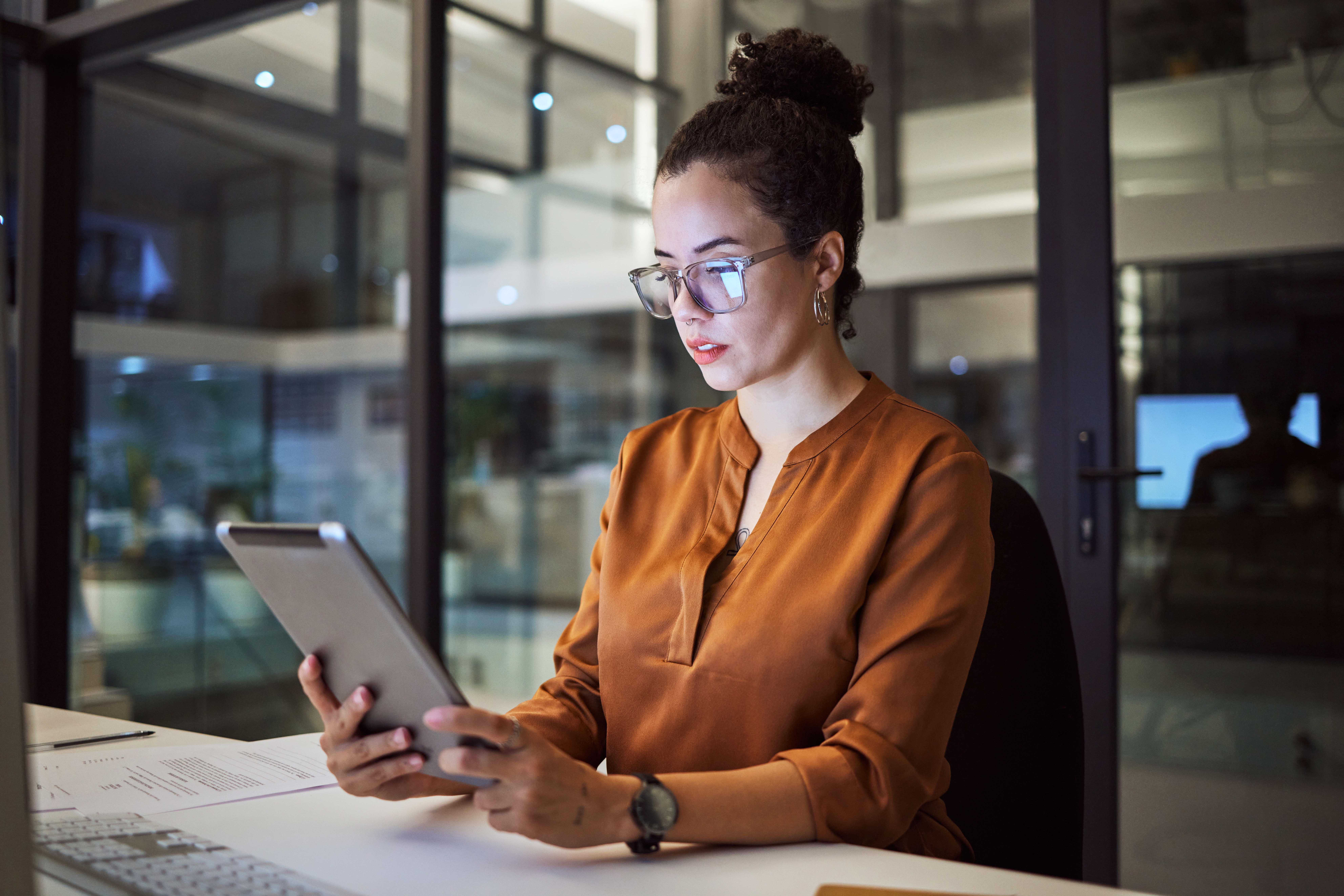 Professional woman using an iPad in an office environment for HR and compliance tasks.