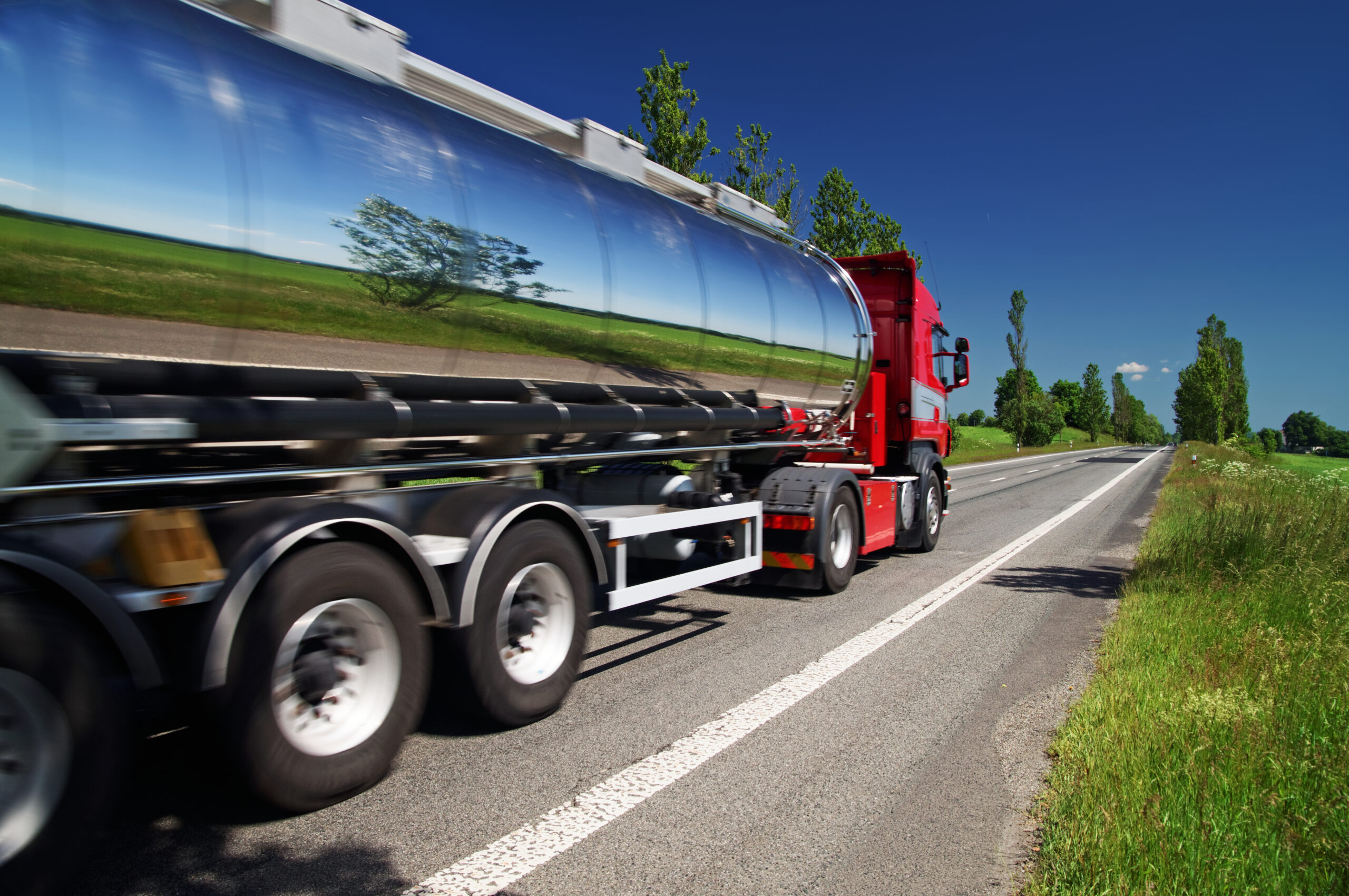 Commercial lorry driving on a road with blue skies.