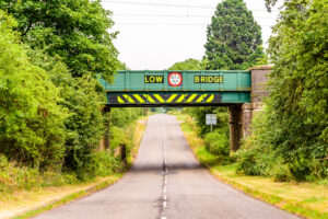 Low railway bridge warning sign on a rural road.