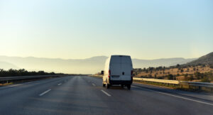 A light goods vehicle on a motorway with a driver using a digital tachograph unit.