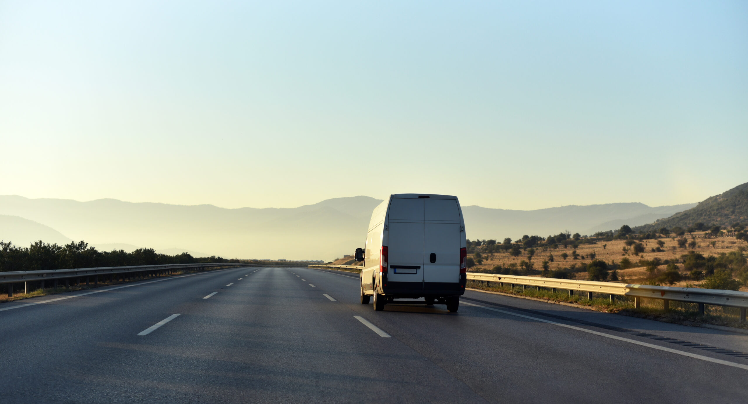 A light goods vehicle on a motorway with a driver using a digital tachograph unit.