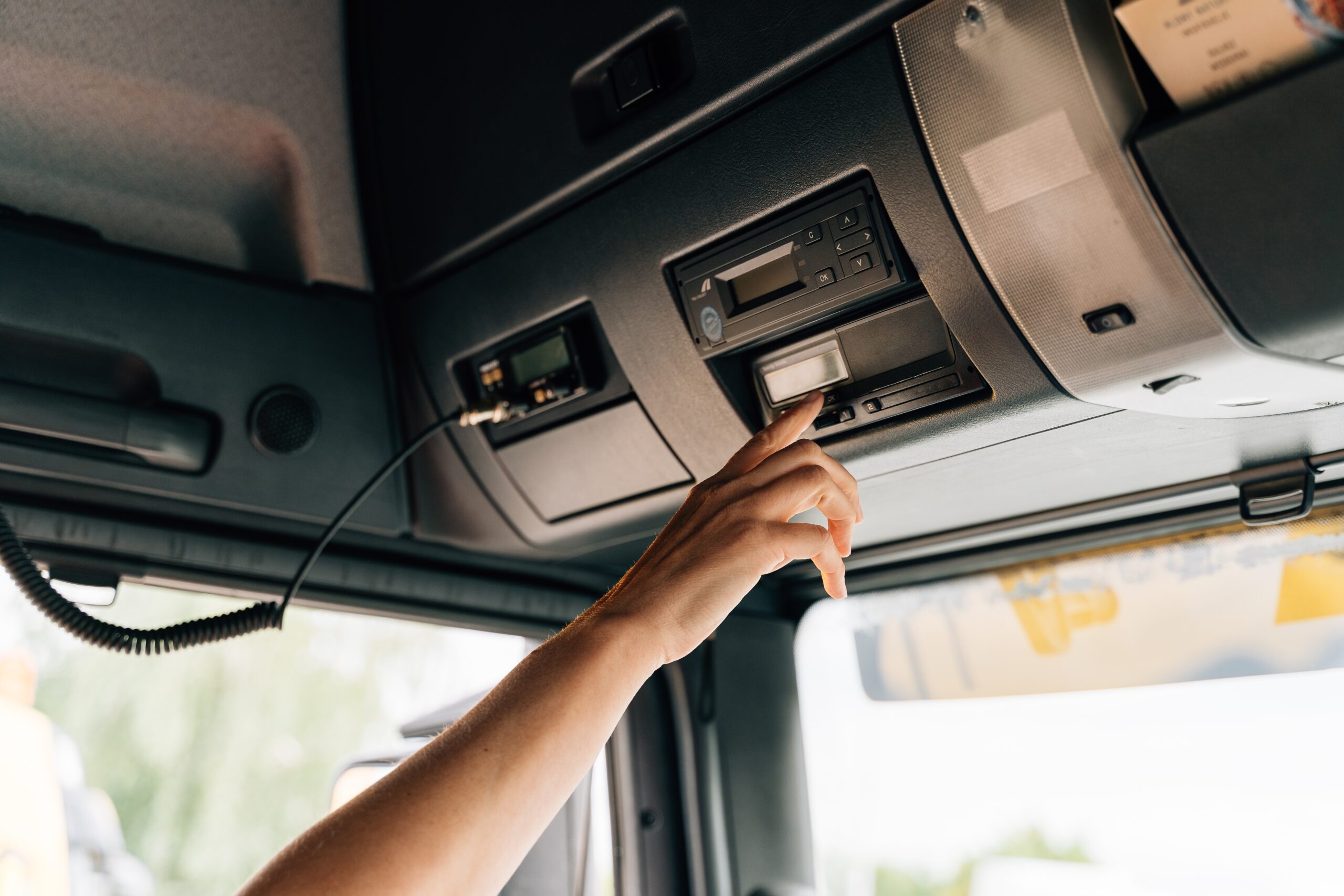 HGV driver using a digital tachograph in a truck cab.